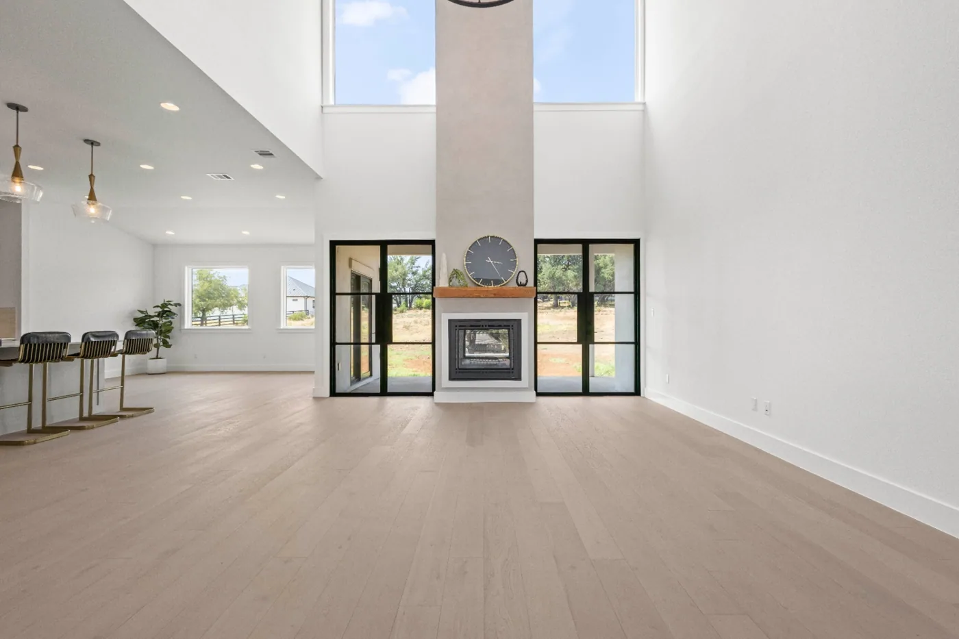 Open-concept living and kitchen area with a floor-to-ceiling stone fireplace surround in the Chipshot custom home by Atlas Custom Homes in Austin, Texas